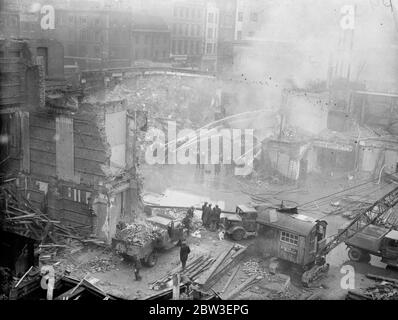 Un incendio feroce all'edificio demolito in Tottenham Court Road , Londra . I vigili del fuoco addestrano i loro tubi flessibili sui detriti . 12 gennaio 1935 Foto Stock