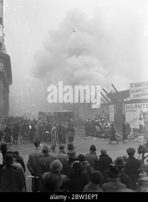 Una folla guarda il fuoco feroce dell'edificio demolito in Tottenham Court Road , Londra . 12 gennaio 1935 Foto Stock