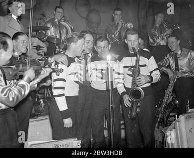 I giocatori di hockey su ghiaccio olimpico britannico a cantare in onda di band di danza . Tre dei giocatori di hockey su ghiaccio che hanno aiutato la Gran Bretagna a vincere nei Giochi Olimpici invernali cantano con la Romany Band in una trasmissione la prossima settimana . Sono Jimmy Foster , portiere , John Howard , Forward , e Joe Beaton , che è capitano dei Richmond Hawks . Spettacoli fotografici , da sinistra a destra , Jimmy Foster , Raymond Doughty , cantanti della band Romony , Joe Beaton , e John Howard che provano a Londra per la loro trasmissione . 23 marzo 1936 Foto Stock