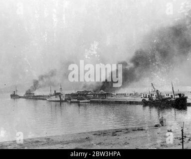 Nave da guerra del governo Bombard Algeciras nella guerra civile spagnola . Con l'incrociatore ribelle dato nelle vicinanze, la nave da guerra governativa Jaime i bonbardment, la città di Algeciras, situata a cinque miglia ad ovest di Gibilterra. Non prima che i banchine fossero stati danneggiati in modo esteso e la città fu Jaime i scacciata da aerei ribelli . Il consolato britannico della città fu gravemente danneggiato e il Console e sua moglie ebbero scappatesi stretti . I residenti di Gibilterra guardavano il bombardamento dai tetti delle loro case . Foto : la banchina ardente di Algeciras dopo il bombardamento . 10 ago 1936 Foto Stock