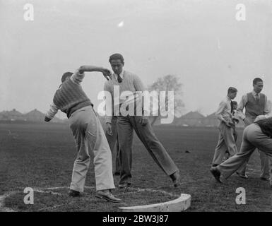 Gli atleti famosi allenano gli studenti alla scuola di eventi sul campo . Atleti famosi stanno comportando come istruttori alla scuola di eventi di campo alla Thames Valley County School , Twickenham . Lezioni e consigli vengono dati ai ragazzi su lancio di giavellotto , messa del peso e altri eventi . Foto spettacoli , ragazzi ricevere istruzioni per mettere il peso da MR B Prendergast (maglione bianco) , un esperto di discussione della London University . 14 aprile 1936 Foto Stock