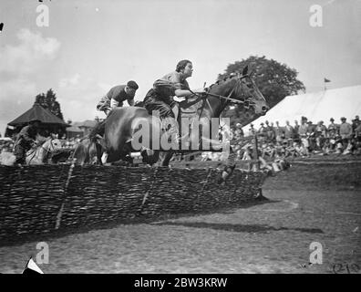 Abito da fantasia Steeplechase a Haywards Heath Gymkhana ! Spettacoli fotografici : indossando un costume da fantasia, Miss Sheila Price prende il suo pony Polymint sopra gli ostacoli in un magnifico salto seguito da MR . G . R . Prezzo durante la gara di Costume alla mostra estiva della Haywards Heath Horticultural Society a Victoria Park , Haywards Heath , Sussex . Nella gara , che è stata una delle novità degli eventi montati nella mostra , tutti i piloti hanno dovuto indossare un abito pieno di fantasia per la steeplechase . 9 Jul 1936 Foto Stock