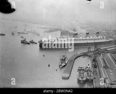 La ' RMS Queen Mary' salpa da Southampton in un viaggio da nubile. Allietato da un quarto di milione di persone che riempiono ogni pollice disponibile dei banchine . La Regina Mary, 80 anni, 000 e' orgogliosa della British Merchant Navy, salpò da Southampton in un suo primo viaggio in America. Era ' vestita su tutti ' con bandiere e centinaia di barche impavidite intorno a lei mentre si allontanava . Spettacoli fotografici , una vista aerea della 'RMS Queen Mary', lasciando i bacini di Southampton . 27 maggio 1936 Foto Stock