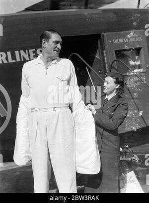 Il cappotto più viaggiato del mondo ! . Realizzato per Victor McLaglen a Londra , l'aeronave Hindenburg lo ha portato attraverso l'Atlantico . Entro quattro giorni dall'ultima cucitura messa in un cappotto sportivo sartoriale a Londra , Victor McLaglen , l'attore del film , indossava il cappotto a Los Angeles . Il cappotto fu volato da Londra a Friedrichshafen , Germania , da aerei di linea , e poi portato a Lakehurst , New Jersey , sulla compagnia aerea Hindenburg . Da lì è stato volato a Los Angeles da American Airlines . Foto spettacoli , Victor McLaglen cercando sul cappotto con l'aiuto di Stewardess Mae Byrne dopo il suo arrivo Foto Stock