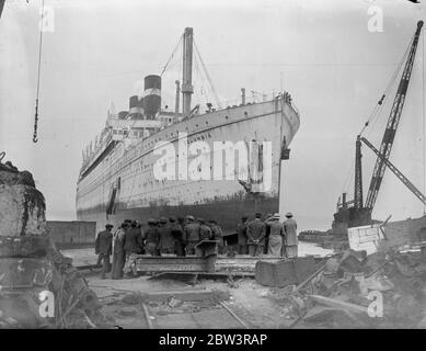 Crane da l'ultima vista di 40 , 000 tonnellate gigante guidato a terra a Bo' Ness una volta una delle navi più prouditi che navigava i sette mari , il 40 , 000 tonnellate di transatlantico americano di lusso Columbia fu fatto correre sotto il suo potere sulla costa scozzese a Bo' Ness per essere rotto . La Columbia è lunga 700 piedi. Foto spettacoli , visitatori che guardano la Columbia dalla gru sopra il ponte . 23 maggio 1936 Foto Stock