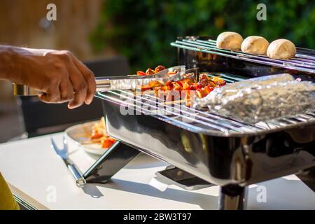 Grigliare su un barbecue ibrido per il barbecue elettrico o al carbone. Spiedini di pollo crudo marinati su spiedini di legno con peperone e cipolla Foto Stock