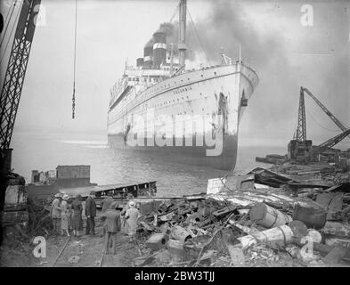 Crane da l'ultima vista di 40 , 000 tonnellate gigante guidato a terra a Bo' Ness una volta una delle navi più prouditi che navigava i sette mari , il 40 , 000 tonnellate di transatlantico americano di lusso Columbia fu fatto correre sotto il suo potere sulla costa scozzese a Bo' Ness per essere rotto . La Columbia è lunga 700 piedi. Foto spettacoli , visitatori che guardano la Columbia dalla gru sopra il ponte . 23 maggio 1936 Foto Stock