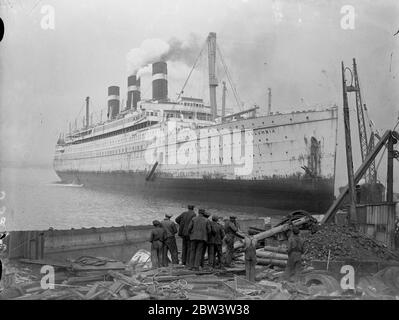 Crane da l'ultima vista di 40 , 000 tonnellate gigante guidato a terra a Bo' Ness una volta una delle navi più prouditi che navigava i sette mari , il 40 , 000 tonnellate di transatlantico americano di lusso Columbia fu fatto correre sotto il suo potere sulla costa scozzese a Bo' Ness per essere rotto . La Columbia è lunga 700 piedi. Foto spettacoli , visitatori che guardano la Columbia dalla gru sopra il ponte . 23 maggio 1936 Foto Stock