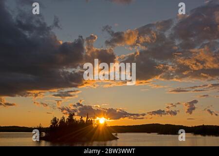 Sole che si staglia attraverso le nuvole al tramonto sul lago Saganagons nel Questico Provincial Park in Ontario Foto Stock