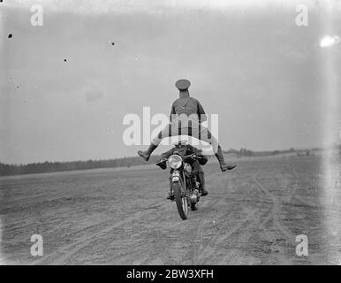 I London Divisional Signals (City of London Signals), Territorials, provano la mostra di trick moto equitazione a Mons Barracks, Aldershot, in preparazione al Royal Tournament, che si apre a Olympia il 27 maggio. La foto mostra uno dei motociclisti che cavalcano tra le gambe di un altro uomo - versione moderna del cammello che passa attraverso l'occhio dell'ago. 27 marzo 1937 Foto Stock