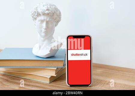 Kiev, Ucraina - 28 maggio 2020: Logo Shutterstock su schermo iPhone X su tavolo di legno con libri e David testa statua. Foto Stock