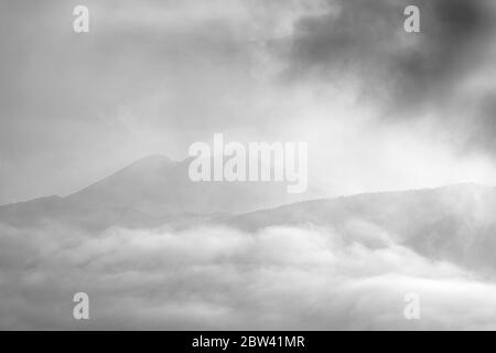 Buio e moody alba prima luce del sole attraverso le nuvole in montagna con Teide e il Pico viejo appena visibile sopra la costa occidentale di Tenerife, CAN Foto Stock