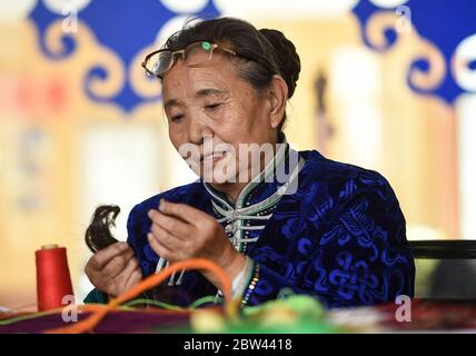 (200529) -- ALXA, 29 maggio 2020 (Xinhua) -- Taogerile mostra come avvolgere i capelli di cavallo in Alxa Banner sinistro, regione autonoma della Mongolia interna della Cina del nord, 29 maggio 2020. Taogerile, 77 anni, è il principale ereditatore di thangka ricamata di capelli di cavallo nella regione autonoma della Mongolia interna. Ha detto che ha ereditato la lavorazione dal nonno e dalla madre. Preoccupato per la cultura morente, Taogerile è stato dedicato all'eredità dell'arte tradizionale. Il ricamo complicato è stato designato come un programma di riduzione della povertà in Alxa Left Banner. Finora, questa lavorazione ha aiutato direttamente Foto Stock