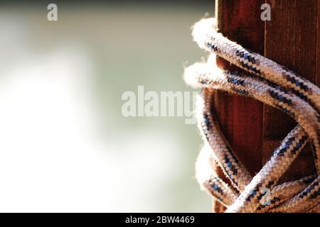 corda legata ad un palo di legno. sfondo è sfocato. Foto Stock