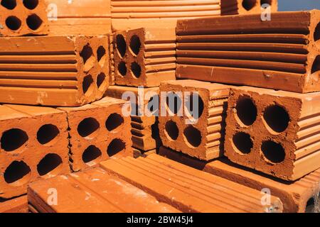 Mattoni rossi cavi impilati in un mucchio, pronti per l'uso in costruzione o per la vendita. Materiale da costruzione. Mattone ripiegato con precisione, foto per la pubblicità. Copia Foto Stock