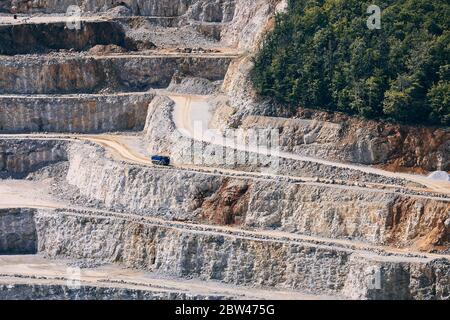 Estrazione di pietre industriali. Camion nel mezzo di una cava enorme. Foto Stock