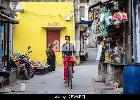 Somnath, Gujarat, India - Dicembre 2018: Un giovane ragazzo indiano guida una bicicletta in un vicolo del mercato nella città vecchia. Foto Stock