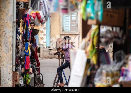 Somnath, Gujarat, India - Dicembre 2018: Un giovane ragazzo indiano in bicicletta in un vicolo del mercato nella città vecchia. Foto Stock