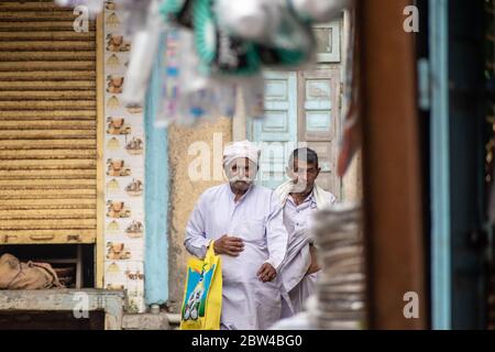 Somnath, Gujarat, India - Dicembre 2018: Un uomo anziano con baffi bianchi che indossano abiti bianchi ed etnici cammina in un vicolo della città vecchia. Foto Stock