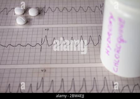 Effetti avversi sul cuore da parte di idrossiclorochina o clorochina. Pillole su un elettrocardiogramma con aritmie cardiache. Contenitore bianco con 'idro Foto Stock
