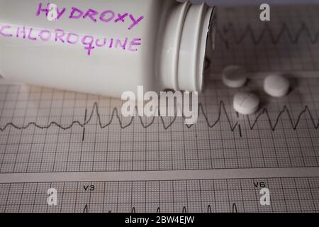 Effetti avversi sul cuore da parte di idrossiclorochina o clorochina. Pillole su un elettrocardiogramma con aritmie cardiache. Contenitore bianco con 'idro Foto Stock