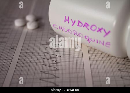 Effetti avversi sul cuore da parte di idrossiclorochina o clorochina. Pillole su un elettrocardiogramma con aritmie cardiache. Contenitore bianco con 'idro Foto Stock