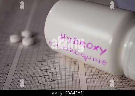 Effetti avversi sul cuore da parte di idrossiclorochina o clorochina. Pillole su un elettrocardiogramma con aritmie cardiache. Contenitore bianco con 'idro Foto Stock