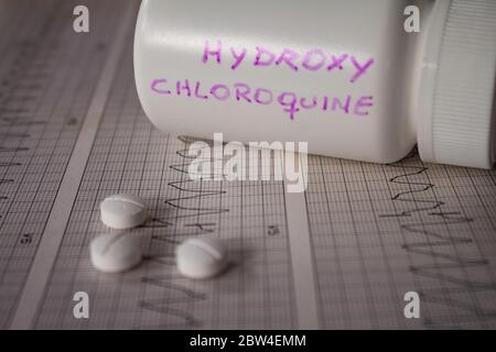 Effetti avversi sul cuore da parte di idrossiclorochina o clorochina. Pillole su un elettrocardiogramma con aritmie cardiache. Contenitore bianco con 'idro Foto Stock