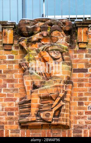 Una scultura in rilievo in mattoni reciso che rappresenta il "tradimento" sulla parete nord del RSC Shakespeare Theatre di Stratford Upon Avon, Inghilterra Foto Stock