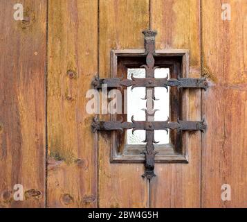 Porta in legno d'epoca con finestra ed elemento decorativo in ghisa. Foto Stock