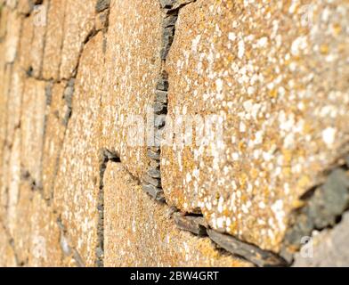 Vecchio muro fatto di pietra arenaria piatta, vista persecutiva. Foto Stock