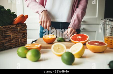 Primo piano foto di una donna caucasica che affetta frutta mentre si fa il succo in cucina Foto Stock