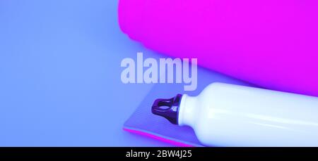 Tappeto da yoga viola brillante e bottiglia d'acqua. Foto Stock