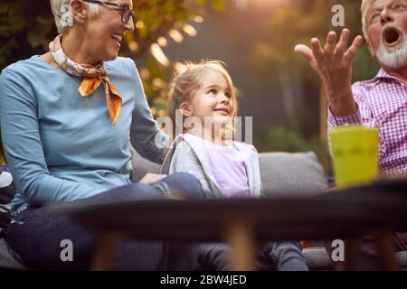 Nonni che giocano con la nipote.Girl sorridente godendosi con i suoi nonni all'aperto a casa. Foto Stock