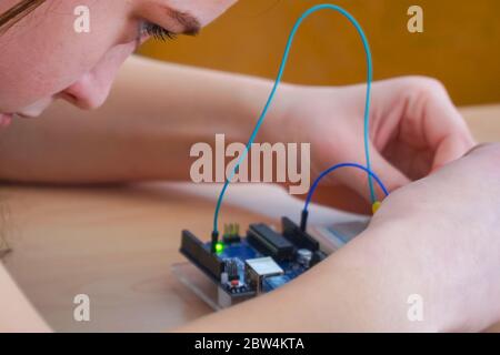 Una ragazza in classe costruisce un dispositivo elettronico Foto Stock