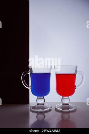 silhouette di due bicchieri su sfondo bianco e nero. Liquido blu e rosso Foto Stock