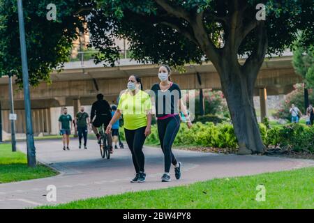 Madre di mezza età e figlia adulta con maschere chirurgiche di protezione del viso che camminano al parco. Nuova normalità durante COVID-19, pandemia di coronavirus. Socia Foto Stock