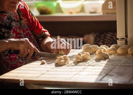 Donna anziana prepara torte su un tavolo nella sua cucina di casa Foto Stock