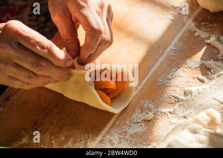 Donna anziana prepara torte su un tavolo nella sua cucina di casa Foto Stock