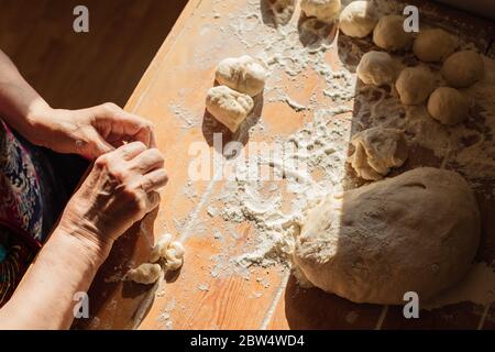 Donna anziana prepara torte su un tavolo nella sua cucina di casa Foto Stock