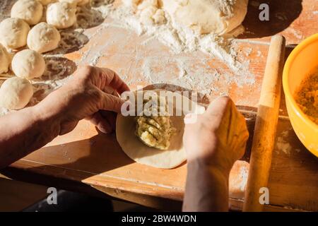 Donna anziana prepara torte su un tavolo nella sua cucina di casa Foto Stock