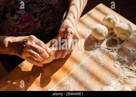 Donna anziana prepara torte su un tavolo nella sua cucina di casa Foto Stock