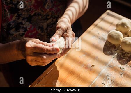 Donna anziana prepara torte su un tavolo nella sua cucina di casa Foto Stock