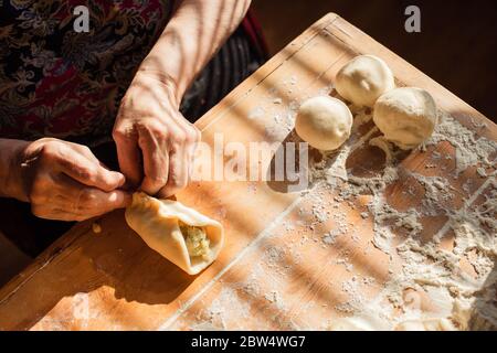 Donna anziana prepara torte su un tavolo nella sua cucina di casa Foto Stock