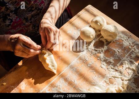 Donna anziana prepara torte su un tavolo nella sua cucina di casa Foto Stock