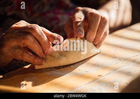 Donna anziana prepara torte su un tavolo nella sua cucina di casa Foto Stock