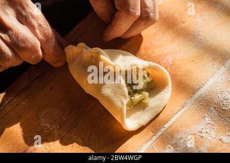 Donna anziana prepara torte su un tavolo nella sua cucina di casa Foto Stock