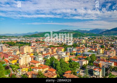 Vista panoramica aerea del quartiere residenziale con edifici della città bresciana e della catena montuosa delle Alpi, sfondo blu cielo nuvoloso, Lombardia, Italia settentrionale Foto Stock