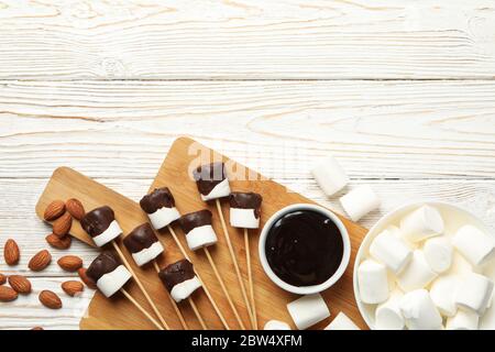 Mandorla e marshmallow in cioccolato su sfondo bianco di legno, vista dall'alto Foto Stock