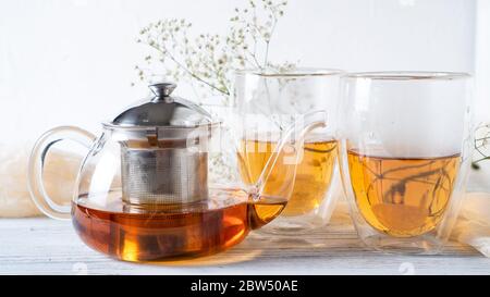 Tè romantico mattutino per coppie. Tè nero in teiera di vetro normale. Tè caldo in tazze a due pareti. Tazze a doppia parete. Foto Stock